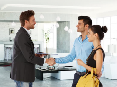 estate agent shaking hands with a couple in an office